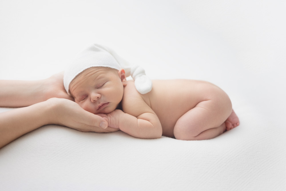 bébé endormi sur le ventre à Tours dans les mains de sa maman avec petit bonnet sur la tête