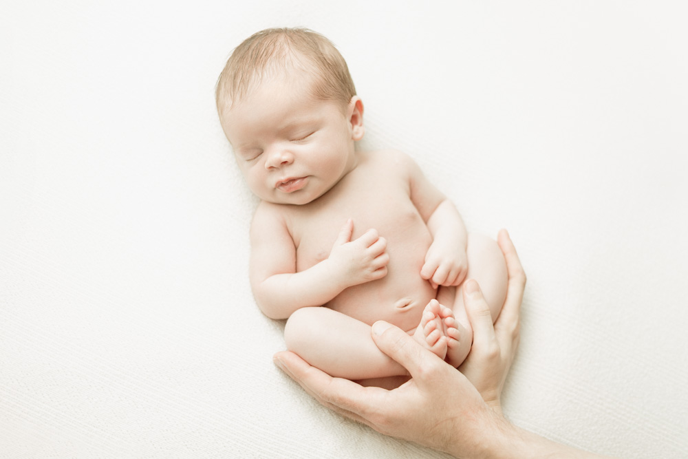 photo de bébé endormi avec les mains des parents