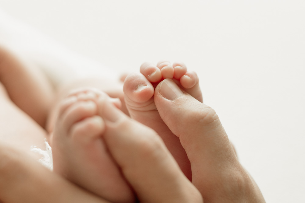 photo de détail pieds de bébé à tours avec mains maman