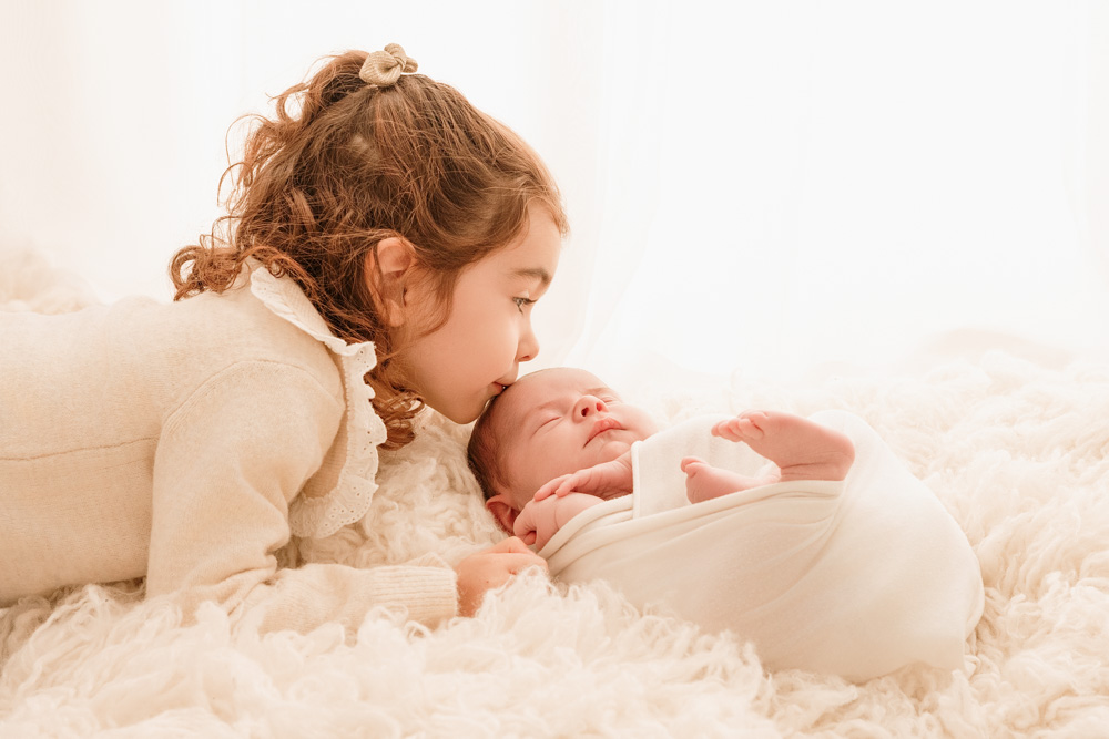 bisous de la grande sœur sur le front de son petit frère