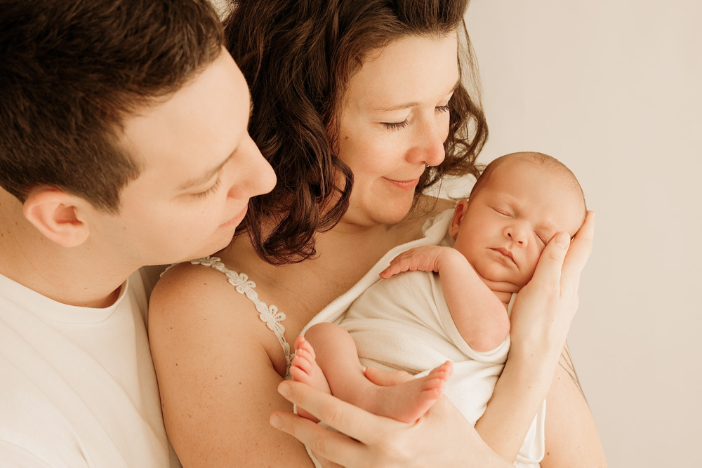 photo de bébé emmailloté avec papa et maman, lumière douce et naturelle
