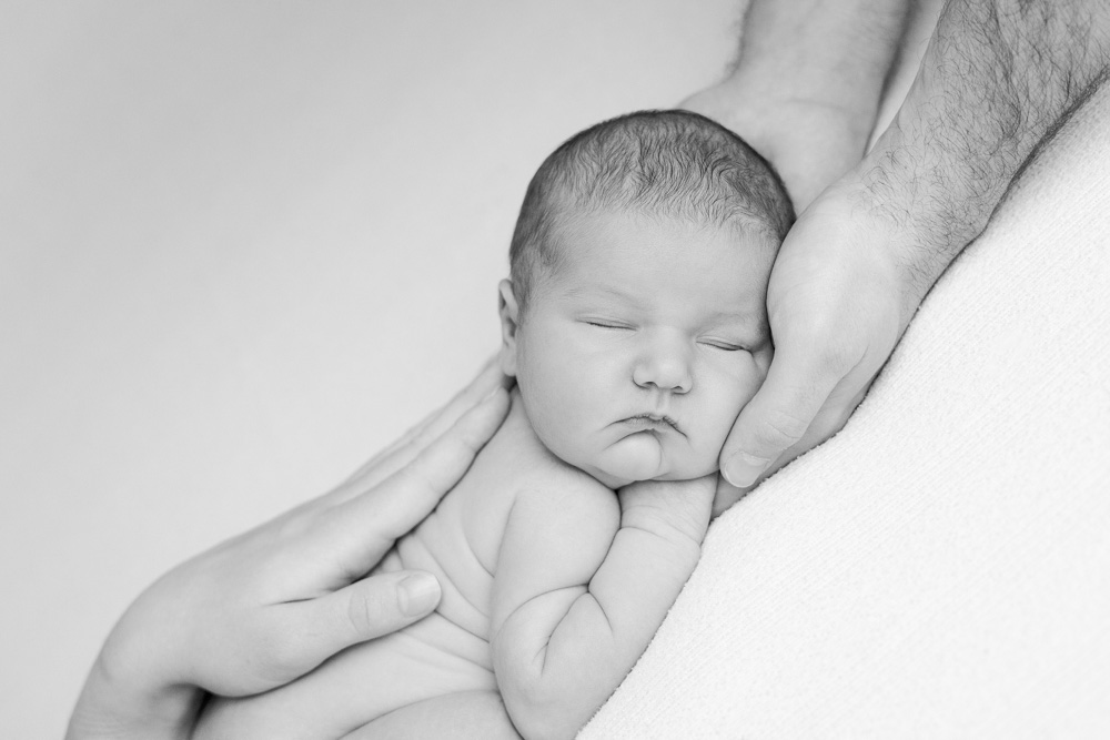 séance photo bébé à Tours, bébé posé nu sur le ventre avec les mains de papa et maman